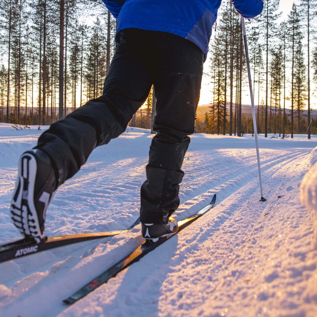 Hiihtoladut ja auringonlasku metsäisen maiseman keskellä, lähikuva jaloista
