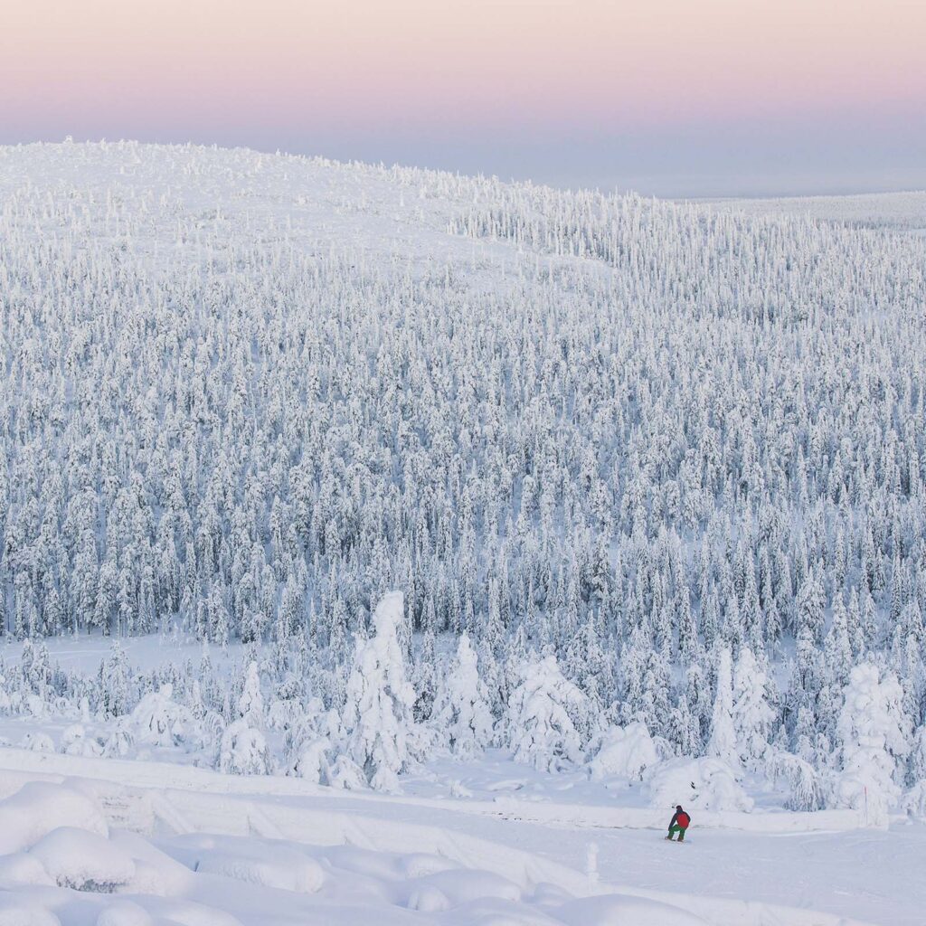 Luminen maisema tunturilta, laskettelija rinteessä